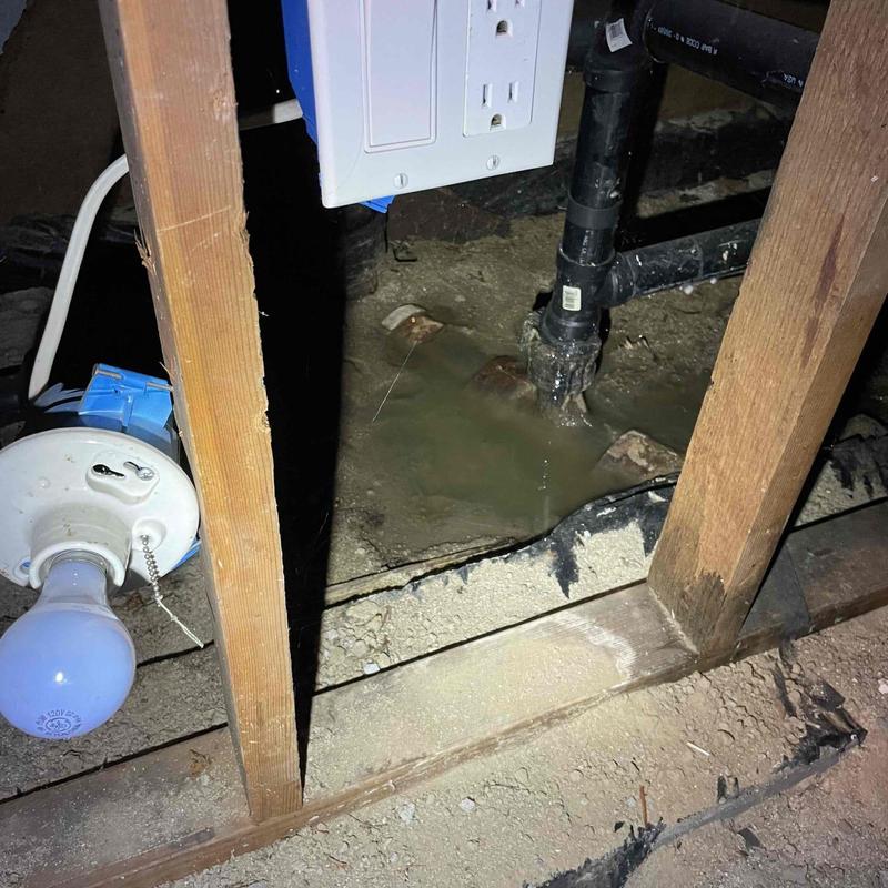 Sewer pipe leaking water in crawl space near outlet