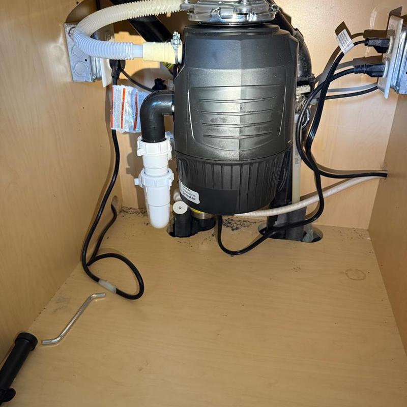 Garbage disposal unit with plumbing and wiring under sink