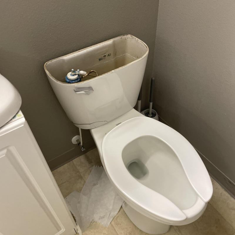 Toilet tank with visible internal components, missing lid