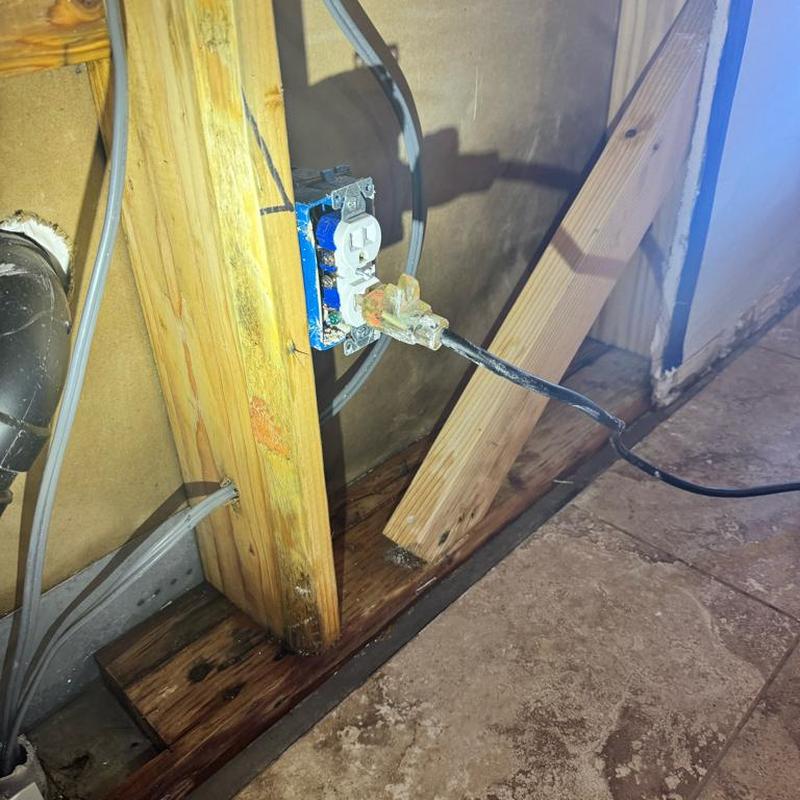 Electrical outlet with water-damaged wood baseboard