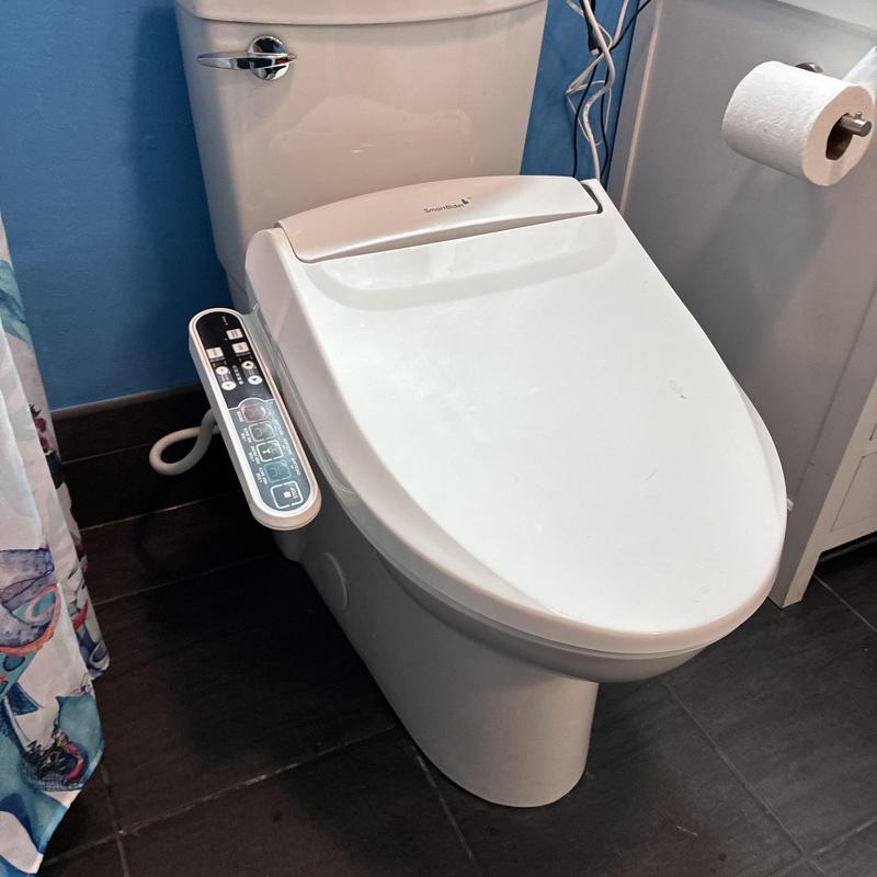 Smart toilet with control panel in bathroom corner