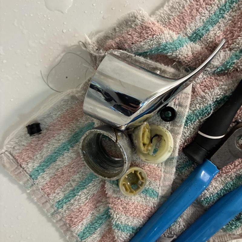 Shower faucet handle and internal parts on towel with tools