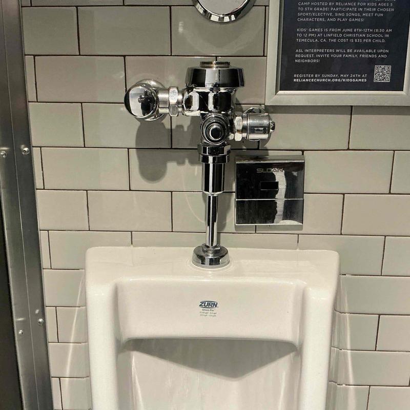 Urinal valve assembly with flushometer in restroom