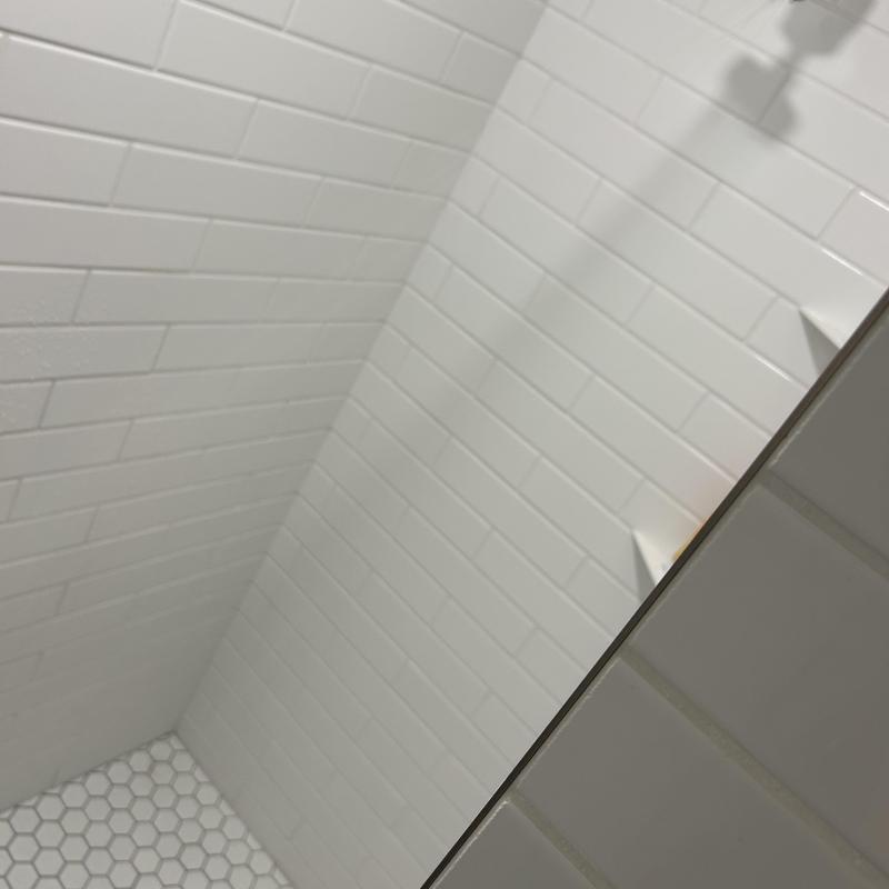Shower drain with white tile walls and hex floor