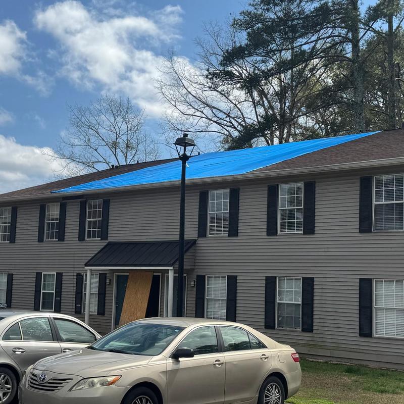 Asphalt shingle roof with blue tarp on apartment building