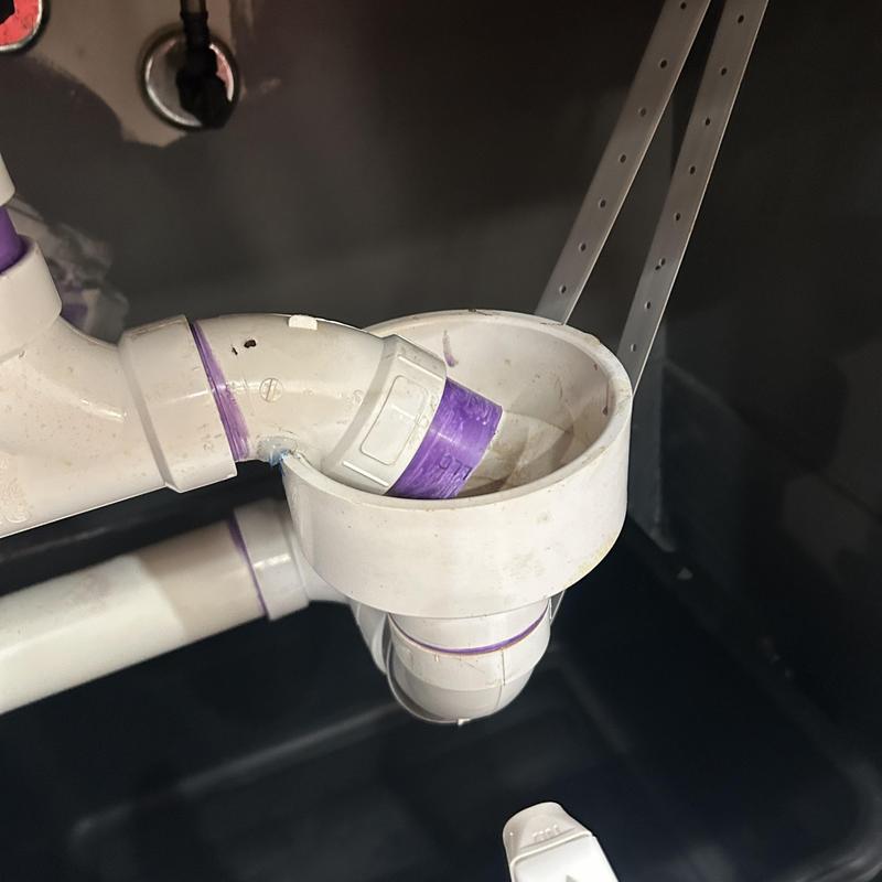PVC drain pipe fitting under sink with purple primer
