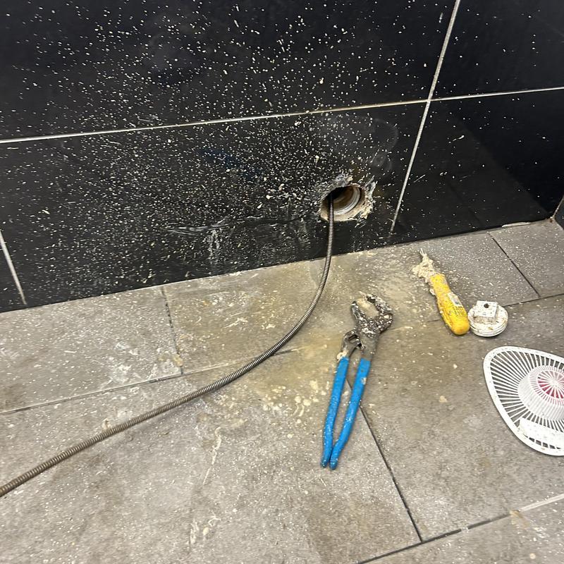 Drain pipe hydro jet cleaning with plumbing tools nearby