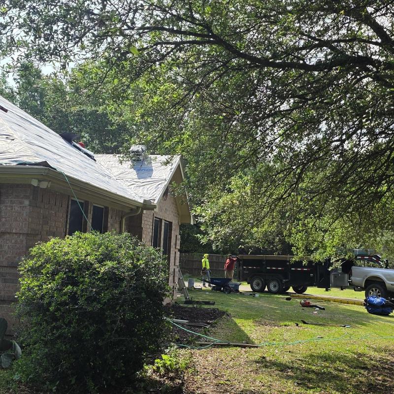 Roof tarp installation on hail-damaged home exterior