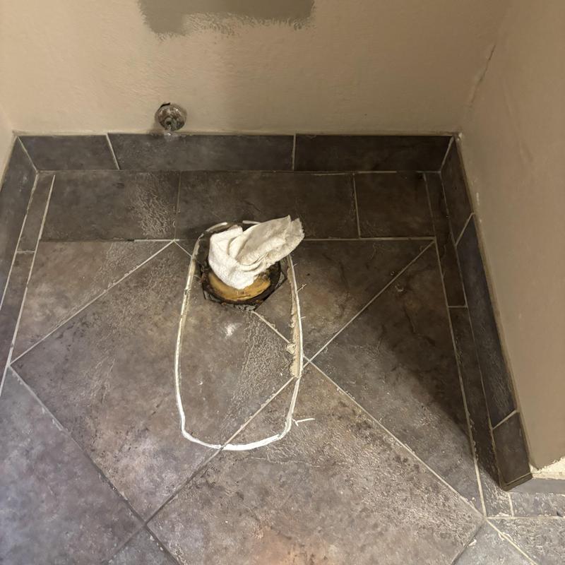 Tile shower pan with exposed drain and patching compound Tile shower pan with exposed drain and patching compound