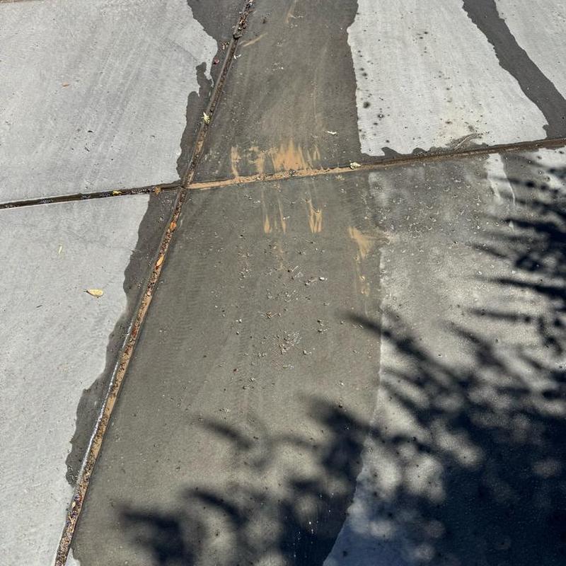 Concrete driveway cleaning showing dirt and water runoff