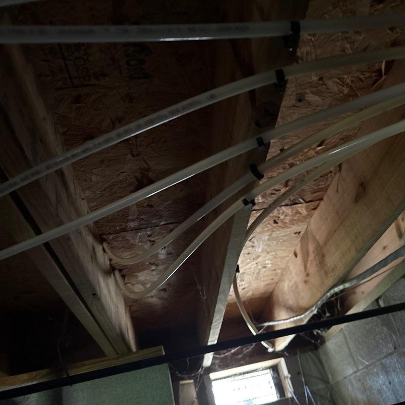 PEX piping installation under floor joists in basement