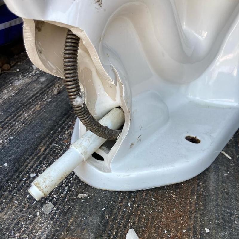 Broken toilet with snake and paper shaft stuck inside