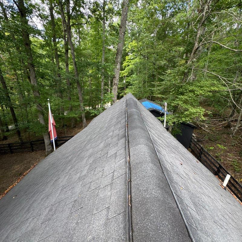 Asphalt shingle roof ridge with visible wear and damage