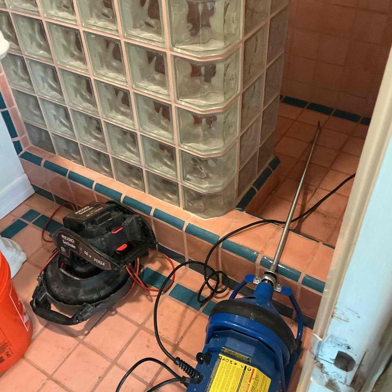 Shower drain line with plumbing auger clearing blockage