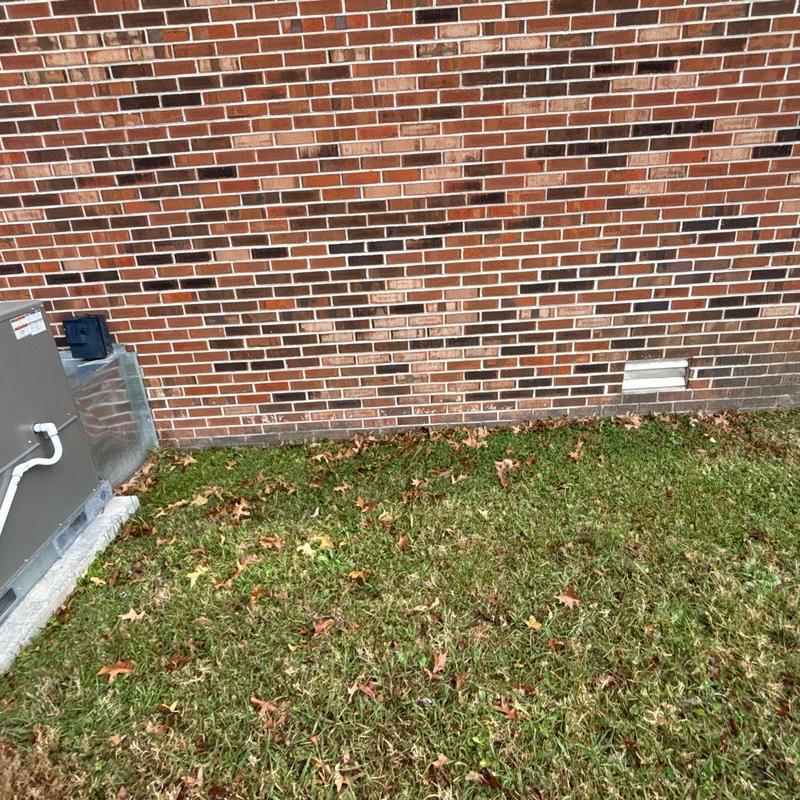 Air conditioner unit next to brick exterior wall