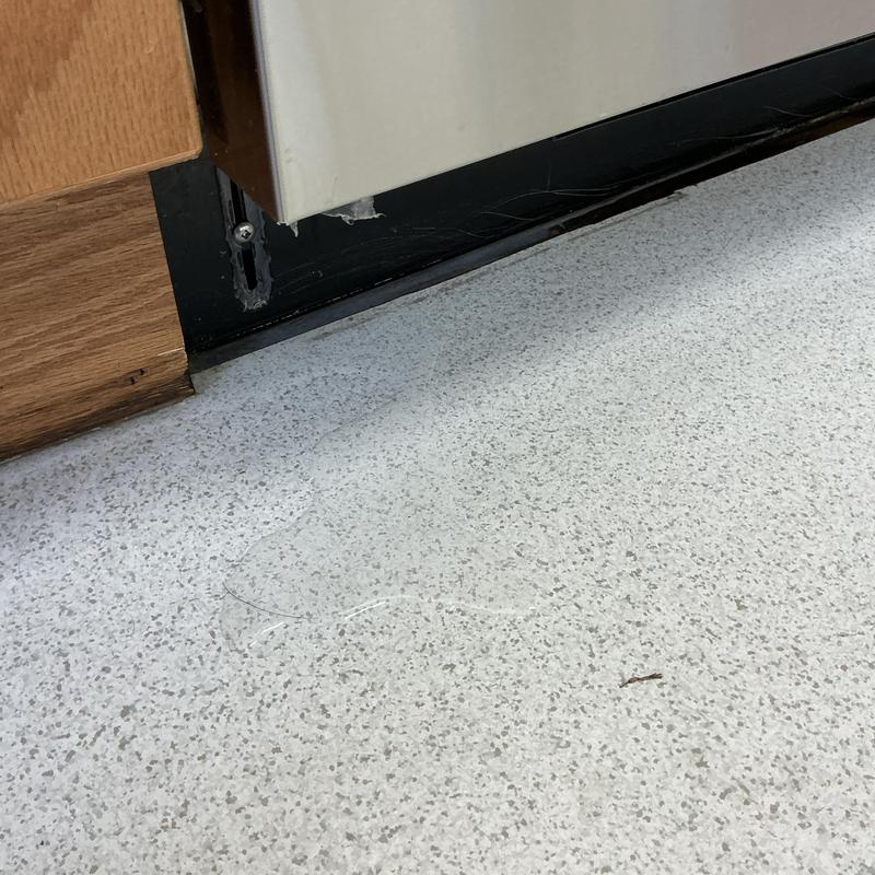 Condensate pump with water overflow on floor near cabinetry