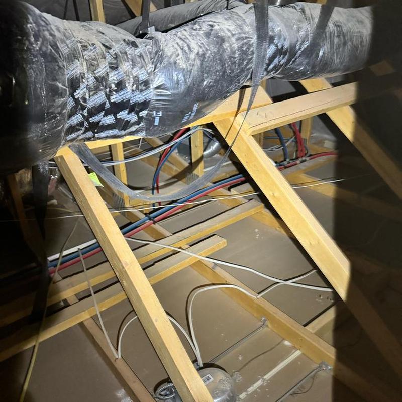 Attic plumbing and ductwork inspection in wooden frame attic