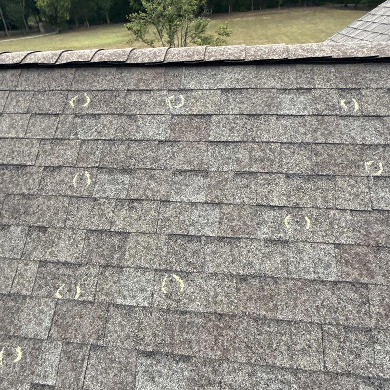 Asphalt roof shingles with hail damage marked in chalk
