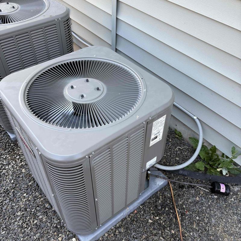 Air conditioner condenser unit with fan on gravel surface