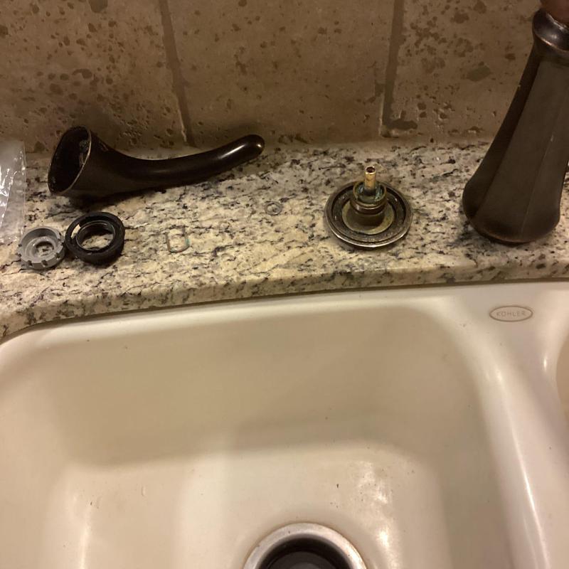 Faucet cartridge replacement with parts on granite counter