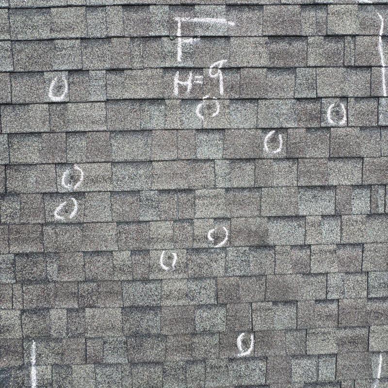 Shingles with hail damage marked for inspection