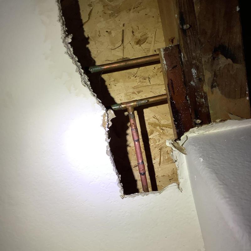 Copper water supply pipes inside wall cavity with drywall cutout