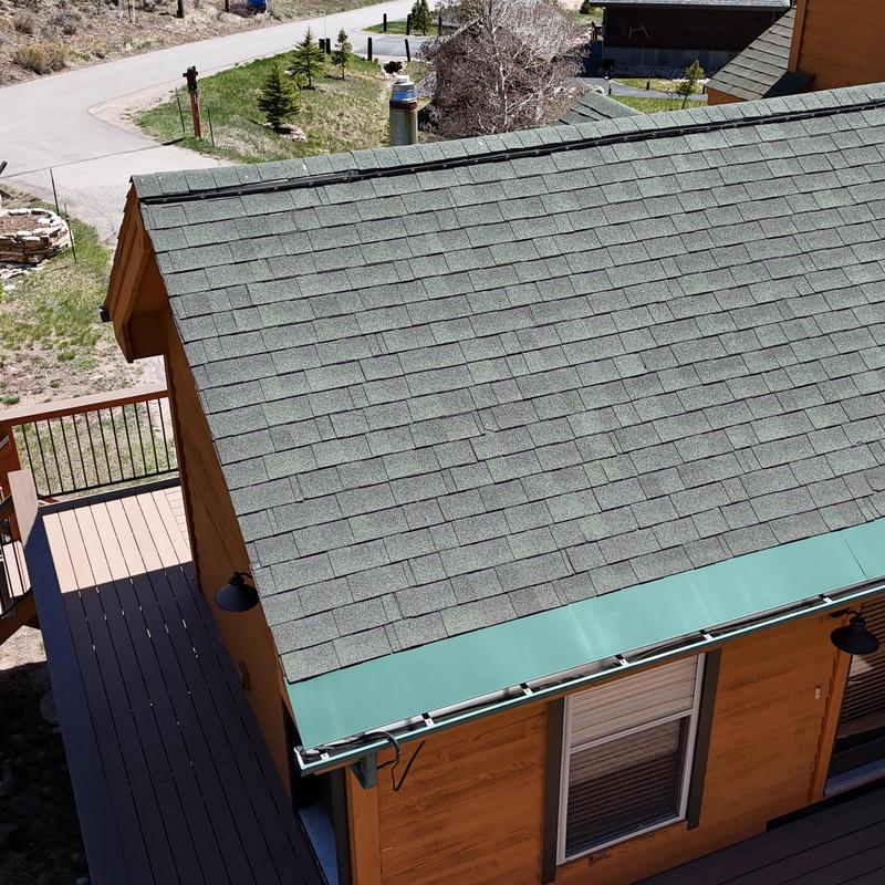Green asphalt shingle roof with metal gutters installation