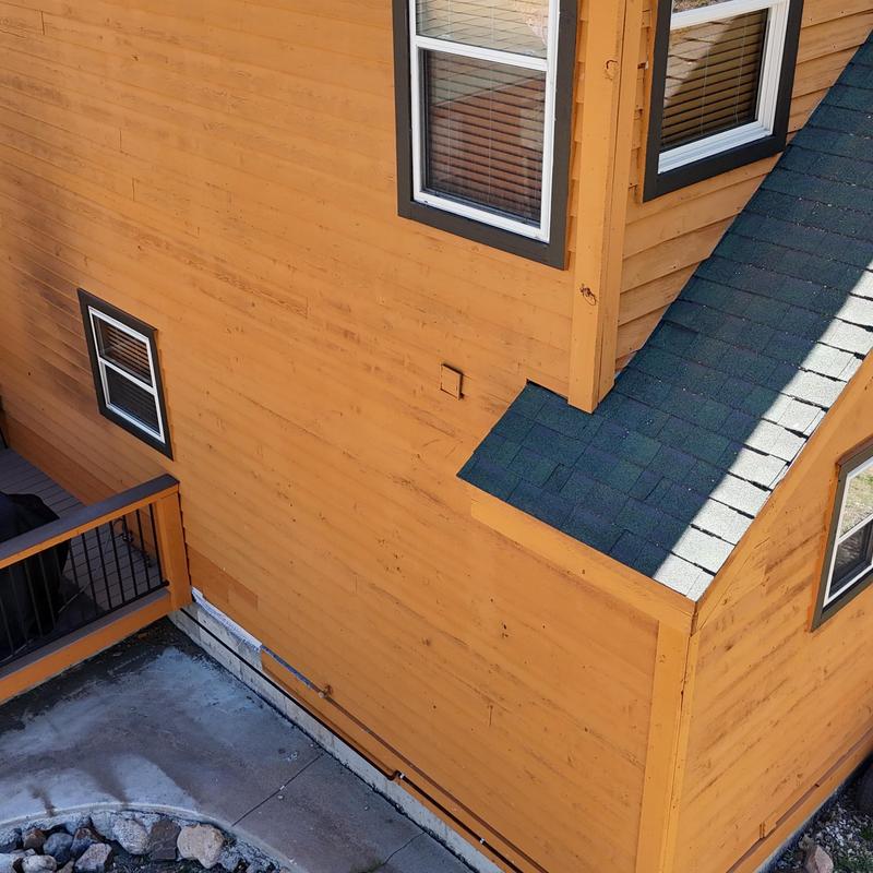 Green asphalt shingle roof on wooden home corner