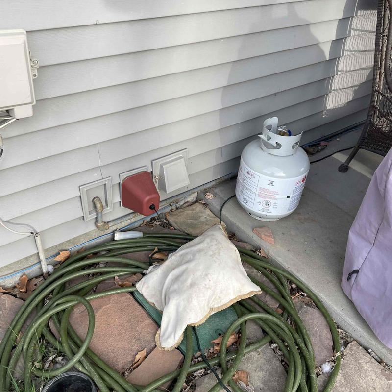 Propane gas tank and hose near house exterior wall