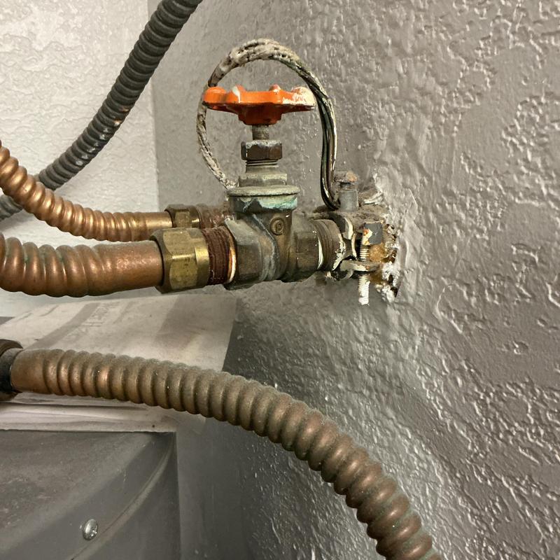 Gas valve with orange handle on wall piping