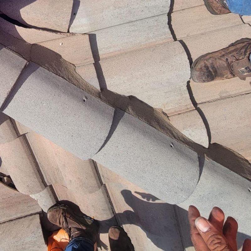Concrete tile roof with cracked tiles and worker boots
