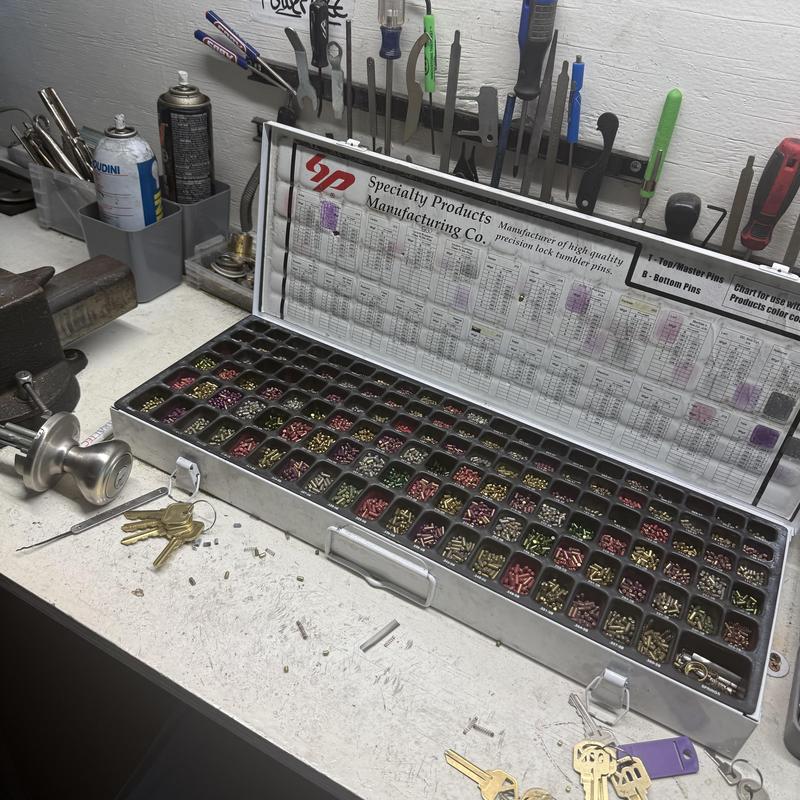 Lock tumbler pins kit with locksmith tools on bench