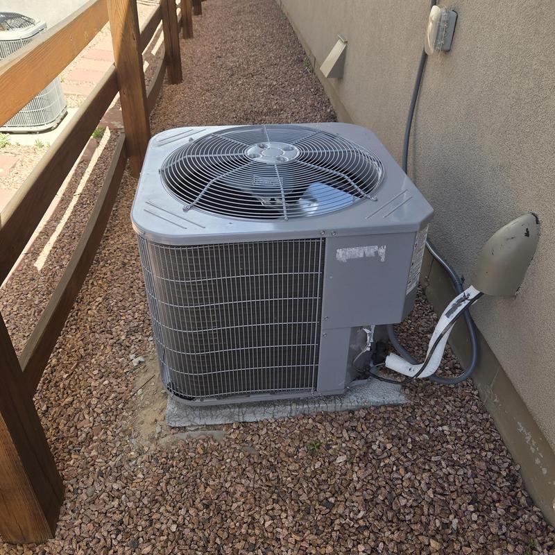 Outdoor AC condenser unit beside house wall