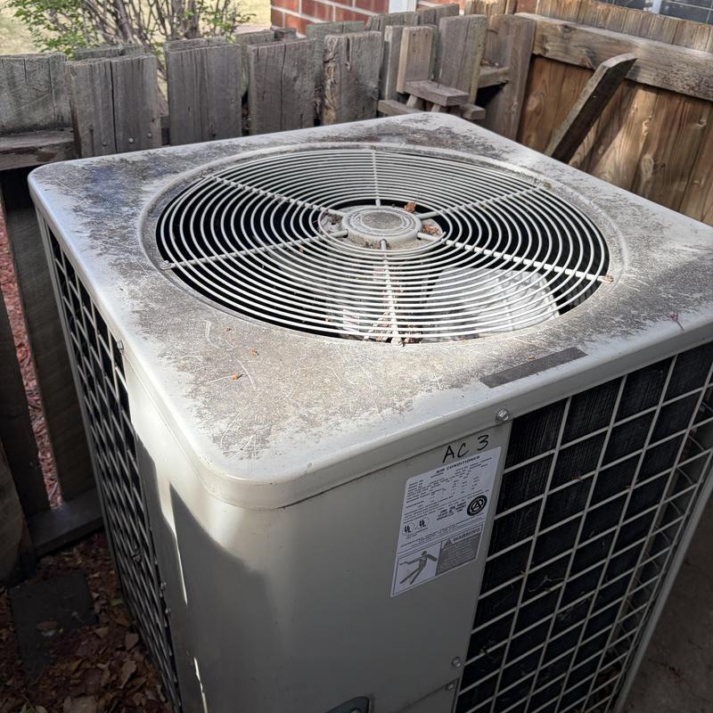 AC unit coil with dust buildup and debris outdoors