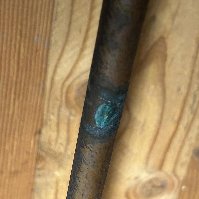Copper water supply pipe with corrosion leak in crawlspace