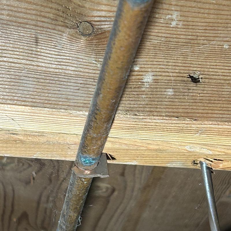 Copper water pipe with corrosion in crawlspace support bracket
