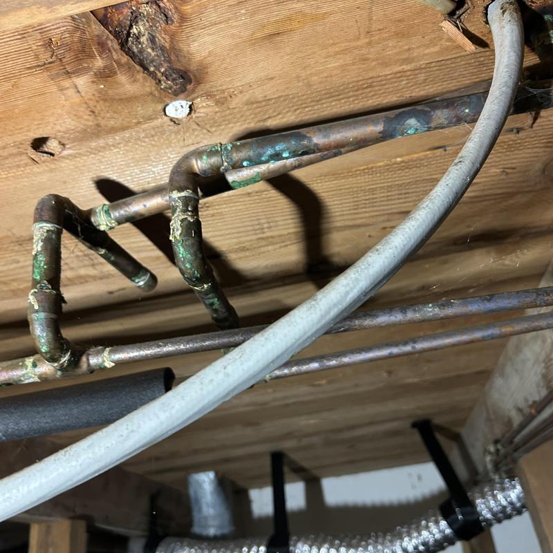 Copper piping with corrosion and leak damage in crawlspace