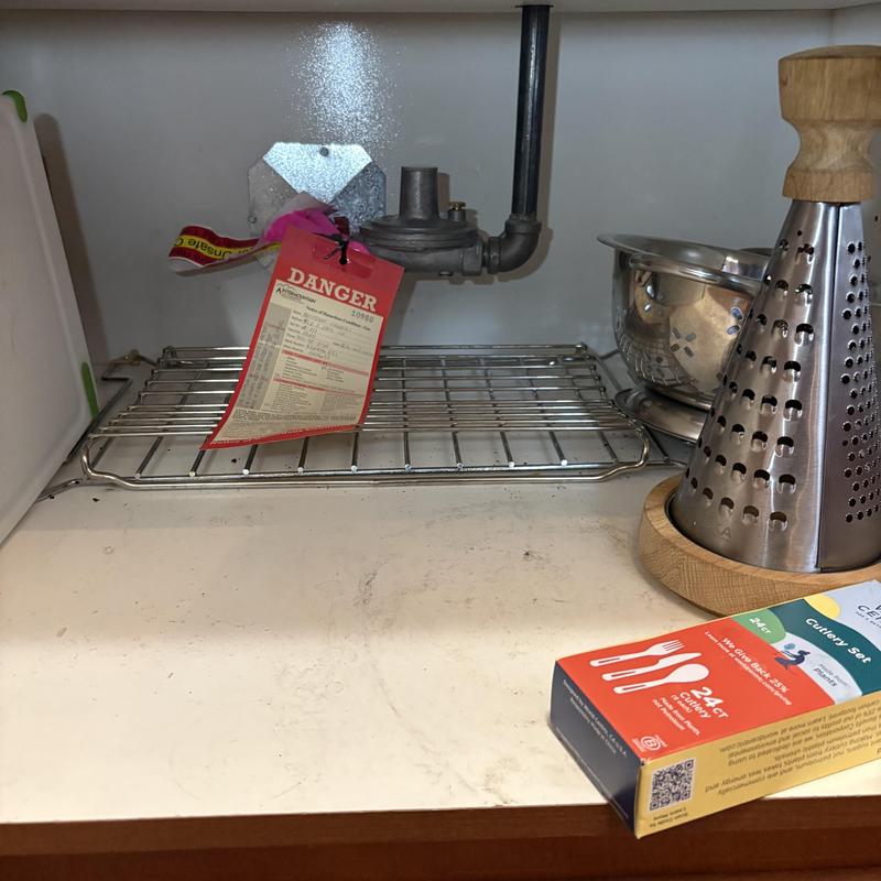 Gas line with danger tag behind stove under cabinet