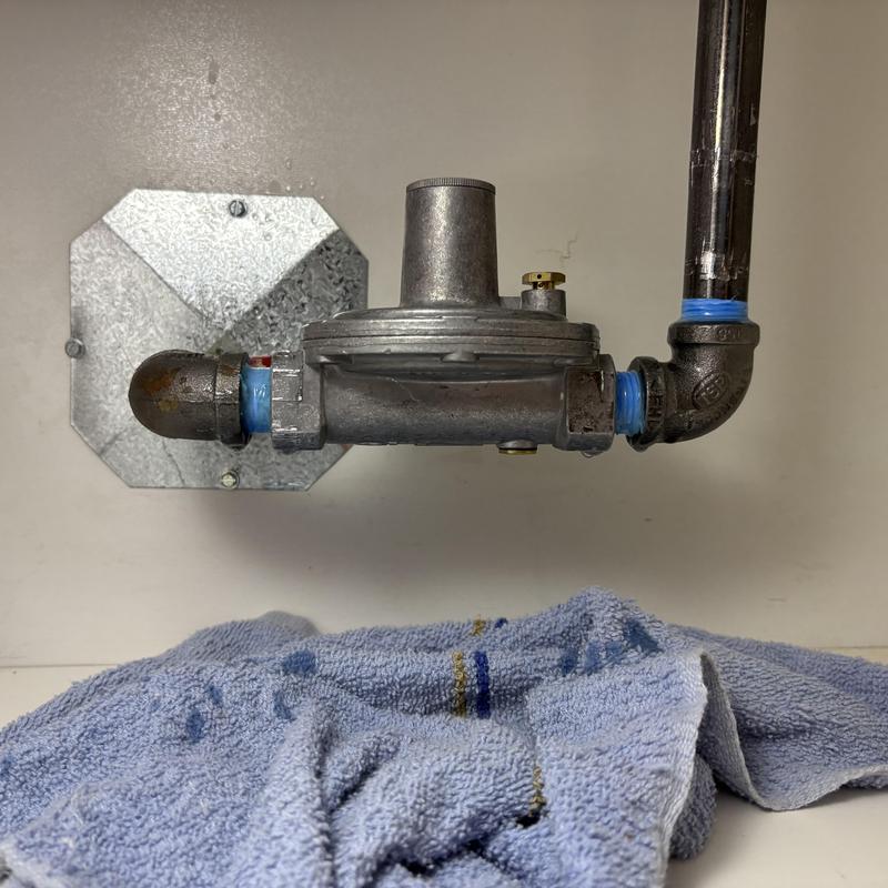 Gas regulator with pipe fittings behind stove in Boise