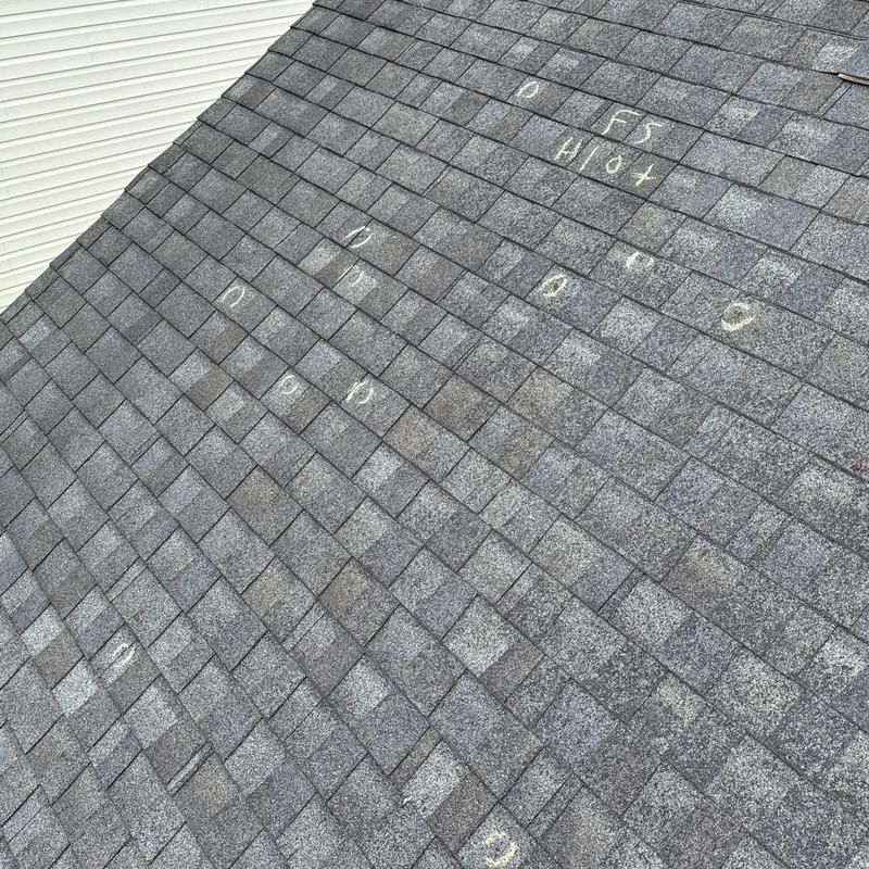 Roof shingles with hail damage marked for inspection