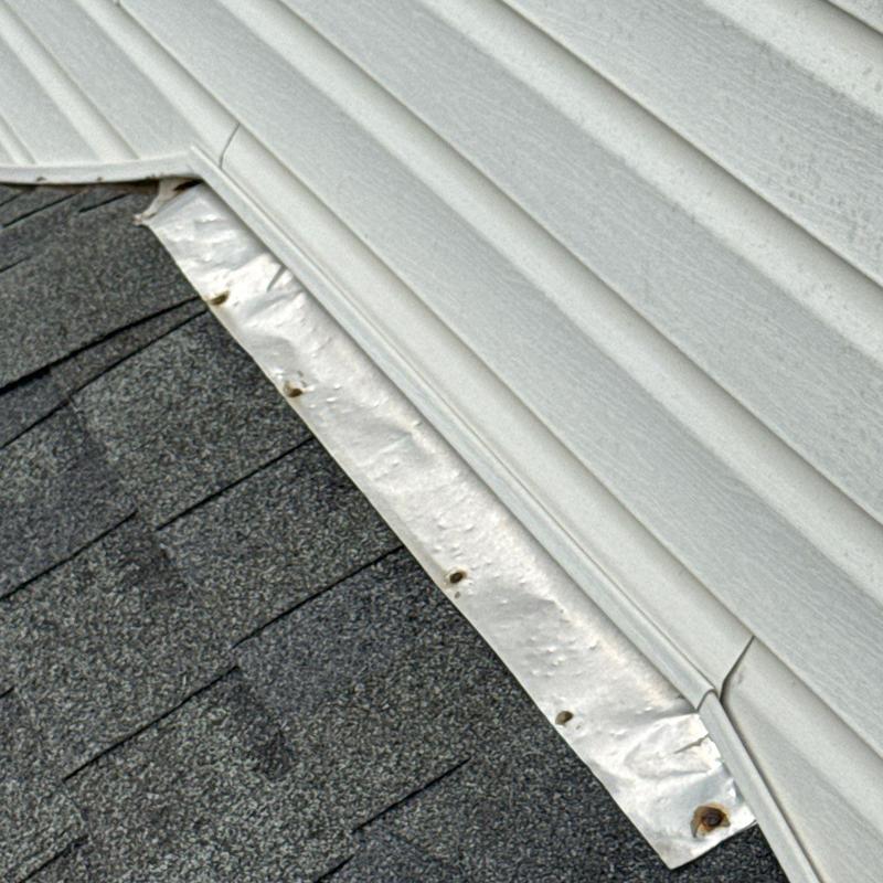 Metal flashing with hail dents on shingle roof edge