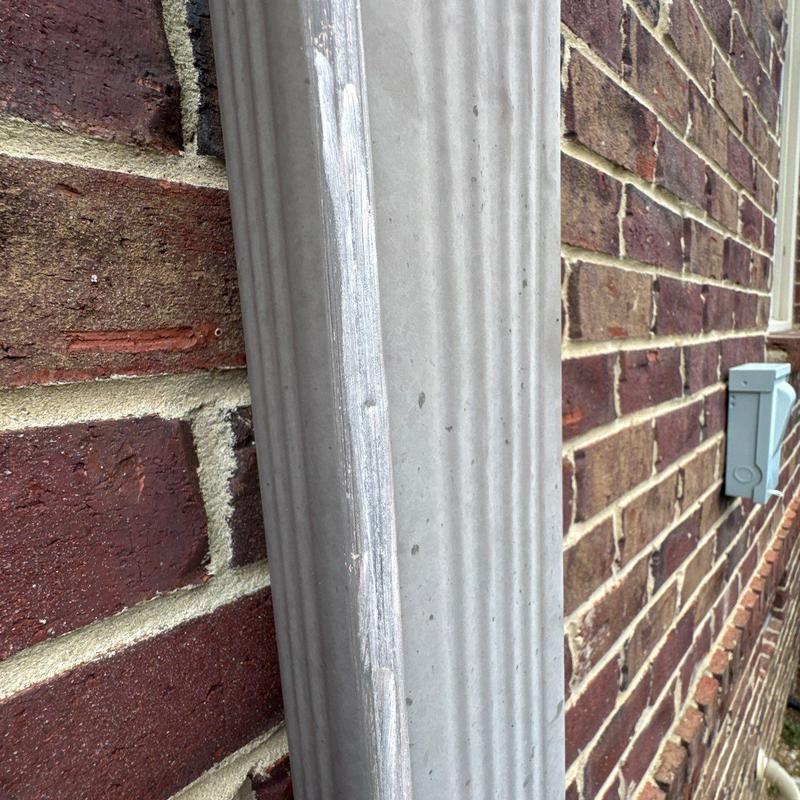 Aluminum downspout dent near brick wall exterior
