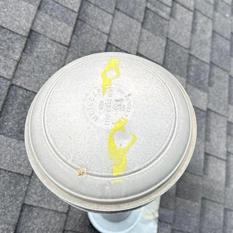 Roof ventilation cap with hail damage markings on shingles