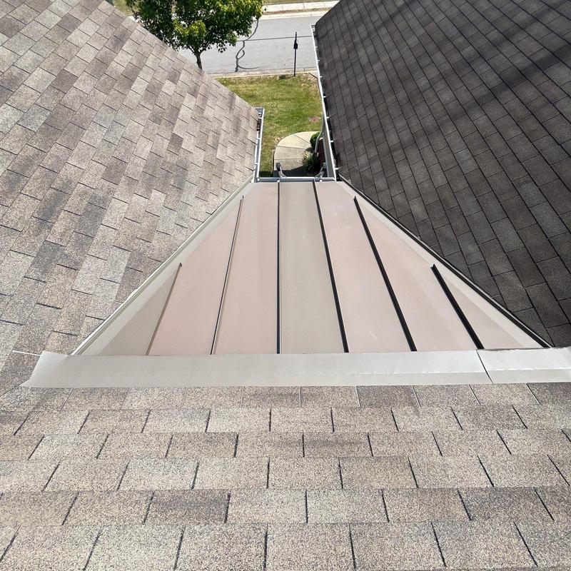 Standing seam metal roof section with asphalt shingles