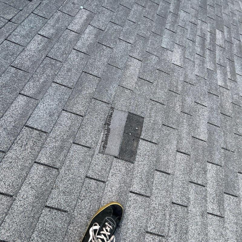 Asphalt roof shingles with hail damage and replacement patch