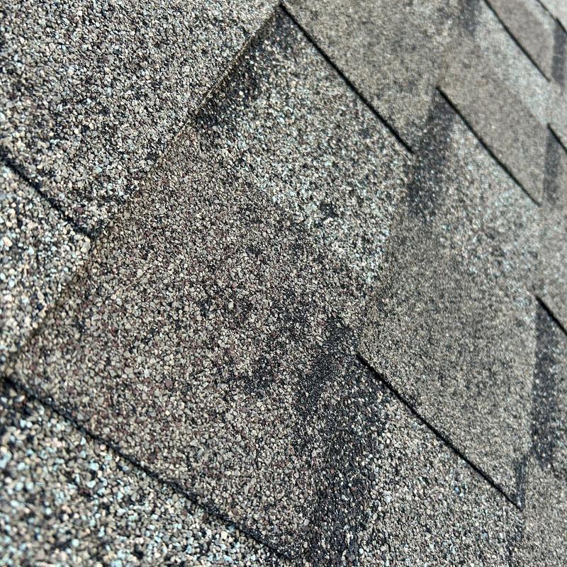 Asphalt roof shingles with hail impact damage close-up