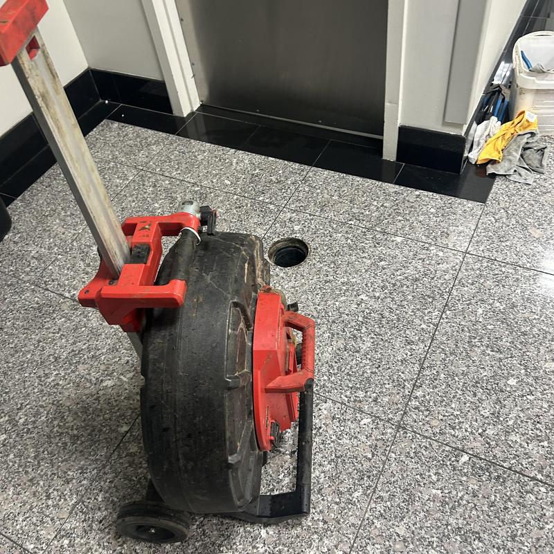 Sanitary drain line cleaning machine near open floor drain