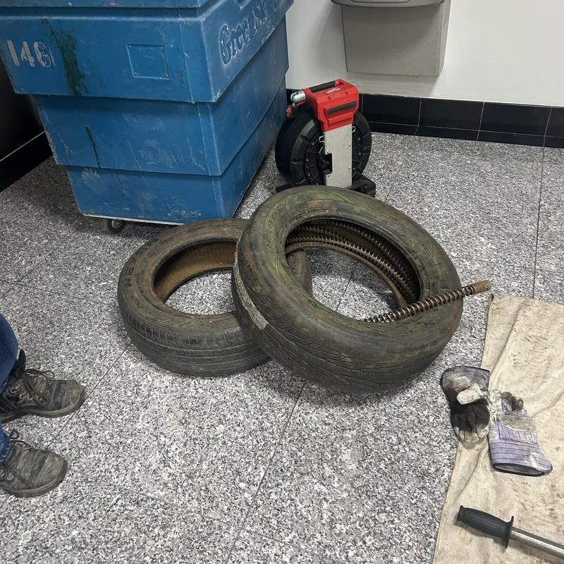 Drain cleaning snakes inside tires with gloves and tools nearby