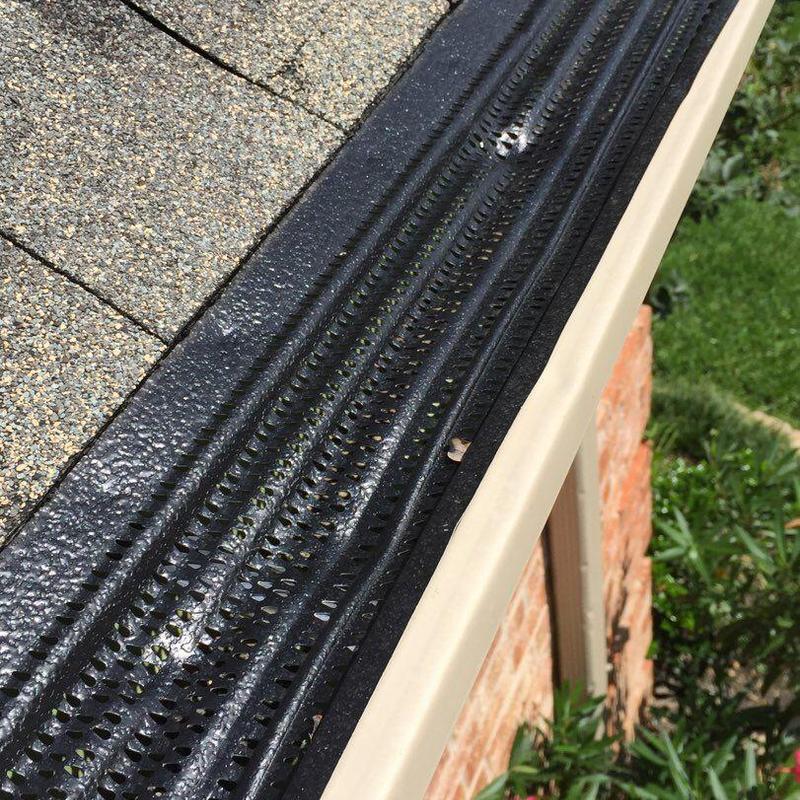 Gutter guard installed on beige rain gutter with shingle roof