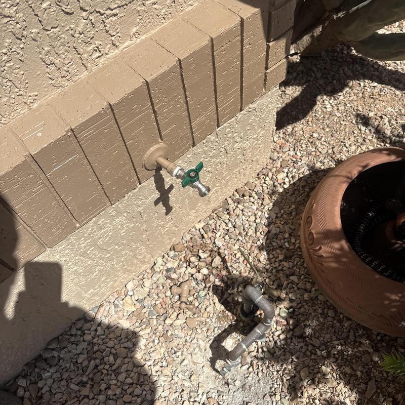 Outdoor hose bib with green handle on house wall Outdoor hose bib with green handle on house wall